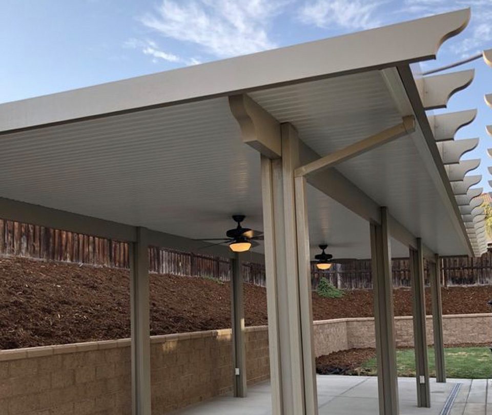 White patio cover next to a small hill with fans