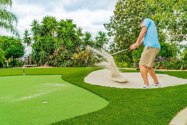 Man inside sand pit putting green