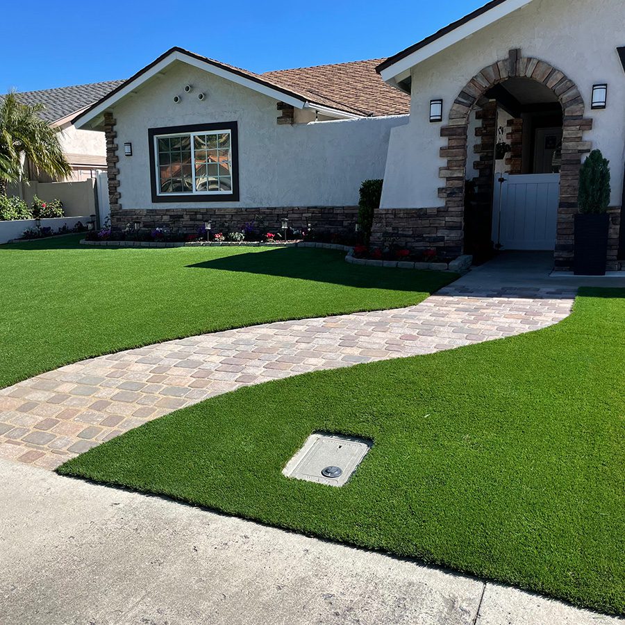 A Front yard with custom pavers and synthetic turf