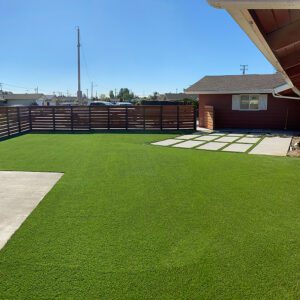 A large suburban backyard with turf and pavers